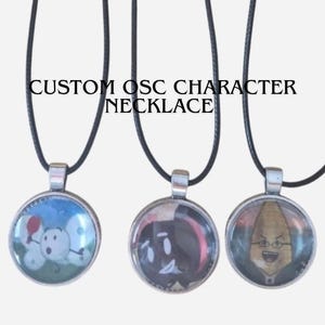 Puede incluir: Tres collares personalizados de personajes OSC con cordones negros. Cada colgante presenta un personaje de dibujos animados diferente en un marco redondo plateado. El texto "CUSTOM OSC CHARACTER NECKLACE" está arriba.