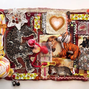 May include: Textile artwork with animal motifs, including a leopard and tiger, set against a red and brown backdrop. The piece incorporates fabric patches, buttons, and crochet elements. The design showcases a variety of textures and patterns.