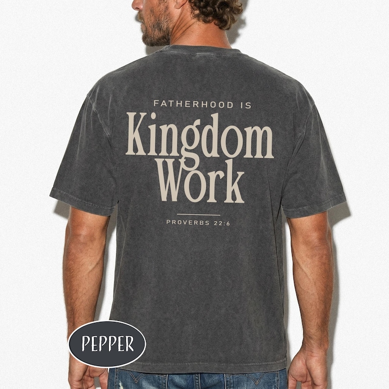 May include: Dark gray t-shirt with the text "FATHERHOOD IS Kingdom Work" and "PROVERBS 22:6" printed on the back. The shirt has a vintage, worn look. The brand name "PEPPER" is printed on the bottom left.