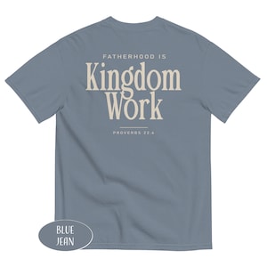 May include: Blue jean short-sleeve t-shirt with the text "FATHERHOOD IS Kingdom Work" in a cream-colored font. The text "PROVERBS 22:6" is below the main text. The shirt is a solid blue color.