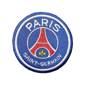 Könnte beinhalten: Gestickter Aufnäher mit dem Logo von Paris Saint-Germain. Der runde Aufnäher hat einen blauen Hintergrund mit weißem Text, der "PARIS" und "SAINT-GERMAIN" lautet. In der Mitte befindet sich ein rotes Eiffelturm-Design und eine gelbe Fleur-de-Lis.