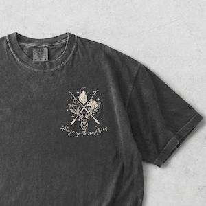 May include: A dark gray t-shirt with a graphic of a deer, wolf, and crossed oars, with the text "Always up to something." The shirt is flat lay