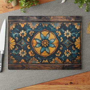 May include: A wooden chopping board with a blue and yellow floral design. The design is painted on the surface of the board and features a large central flower with smaller flowers surrounding it.
