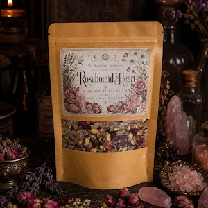 May include: A brown kraft paper pouch containing Rosebound Heart sacred ritual salt. The label features floral illustrations, a sun icon, and the text The Moonlight Apothecary. A clear window reveals a blend of coarse salt, dried flower petals, and herbs.