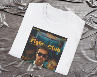 May include: White t-shirt with a graphic print of the movie poster for Fight Club. The poster features the text "Fight Club" in yellow and black letters, and a photo of Brad Pitt in the movie. The poster also includes the text "Mischief, Mayhem, Soup".