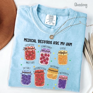May include: Light blue t-shirt with the text "MEDICAL RECORDS ARE MY JAM" and illustrations of jam jars. The jars contain various fruits and the shirt also has the words "accuracy", "compliance", "focus", "details", "organization", "discipline", and "integrity".