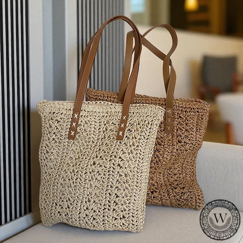 Puede incluir: Dos bolsos tote tejidos con asas de cuero marr&oacute;n. Una bolsa es de color beige claro, la otra es marr&oacute;n. Las bolsas tienen un dise&ntilde;o de tejido abierto y texturizado. Las bolsas est&aacute;n sobre una superficie blanca.
