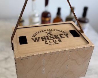 Puede incluir: Una caja de madera con asa de cuero. La caja está grabada con el texto "Southern California Whiskey Club Est. MMXIII".