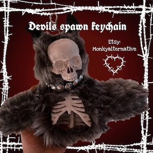 May include: A keychain featuring a skull with a fur-like body and a skeleton chest. The keychain has the text "Devils spawn keychain" and "Etsy: Monkyalternative". The design includes a silver-colored collar.