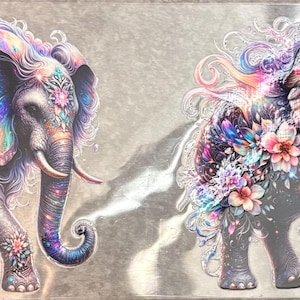 May include: Two identical rectangular stickers featuring a vibrant, artistic illustration of an elephant. The elephant is decorated with swirling, iridescent rainbow-colored patterns, intricate floral motifs in pink and blue, and sparkling accents.