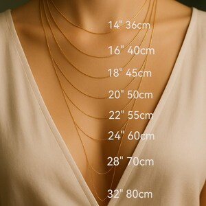 a close-up of a person's neck with multiple gold necklaces of varying lengths, each labeled with its corresponding size in centimeters.