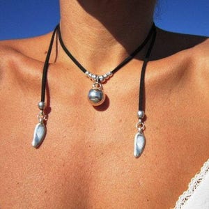 A close-up view of a woman's neck and chest area, wearing a necklace with a pendant and dangling earrings.