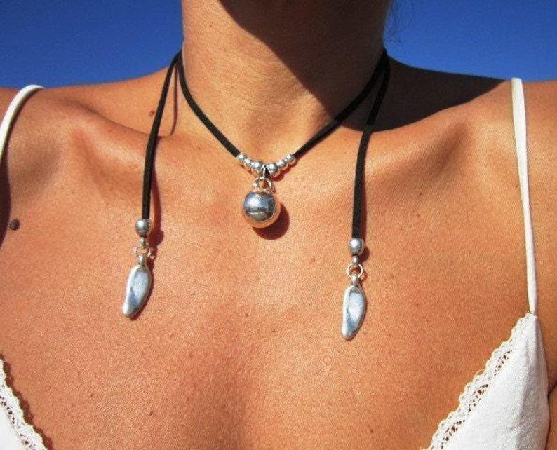 A close-up view of a woman's neck and chest area, wearing a necklace with a pendant and dangling earrings.
