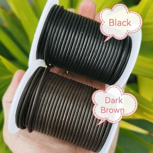 A hand holding two spools of black and brown leather cord, with speech bubbles indicating the color of each spool.