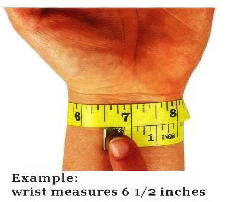 A person's wrist is being measured with a yellow measuring tape, which is wrapped around the wrist and displaying the measurements in inches.