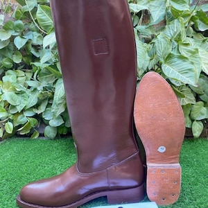 May include: Brown leather riding boots with a square detail on the shaft. The boots have a brown leather sole with a size 10 label.
