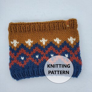 May include: A knitted cowl in shades of brown, navy blue, and rust with a geometric pattern. The cowl features white floral-like designs and the text "KNITTING PATTERN". A small leather tag is attached to the top.