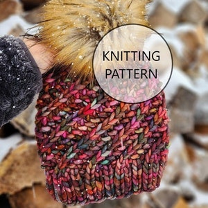 May include: A colourful knitted hat with a fluffy pom pom. The hat is made with a chunky yarn and has a textured stitch pattern. The text "KNITTING PATTERN" is visible in the image.
