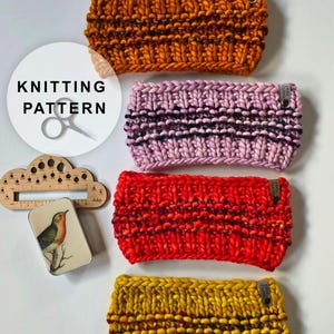May include: Four chunky knit headbands in orange, light pink, bright red, and mustard yellow. Each headband features a textured stitch pattern and a small branded tag. A wooden needle gauge and a small tin with a bird illustration are included.