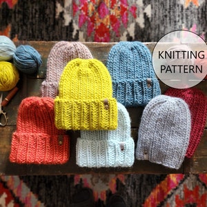 May include: A collection of seven knitted hats in various colours, including red, blue, grey, yellow, and pink. The hats are arranged on a wooden surface with the text "Knitting Pattern" in a circle.