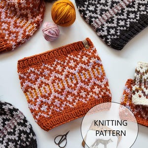 May include: Knitting pattern for a geometric patterned hat and cowl. The pattern features a repeating diamond design in shades of orange, pink, and white. The pattern is available as a digital download.