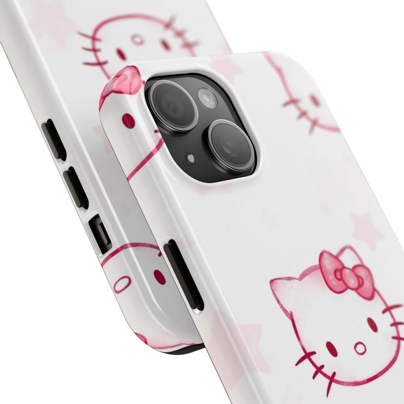 May include: White phone case with a pink Hello Kitty design and star accents. The case has a glossy finish and a close-up view of the camera and side buttons. The design includes Hello Kitty's face and bow.