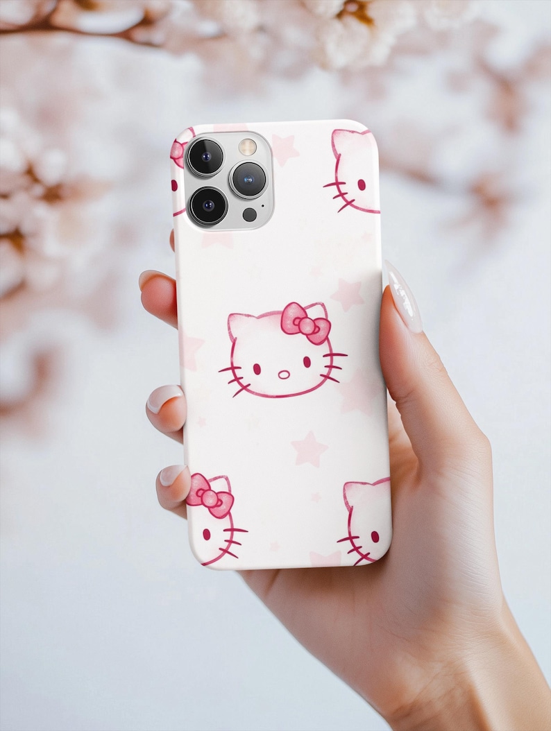 May include: A white phone case with a repeating pattern of pink Hello Kitty faces and bows, and pink stars. The case has a glossy finish and a camera cutout.