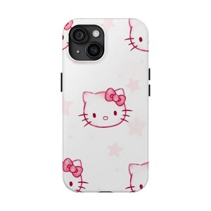 May include: White phone case with a repeating pattern of pink Hello Kitty faces and pink stars. The case has a camera cutout and black side buttons. A cute and playful accessory.