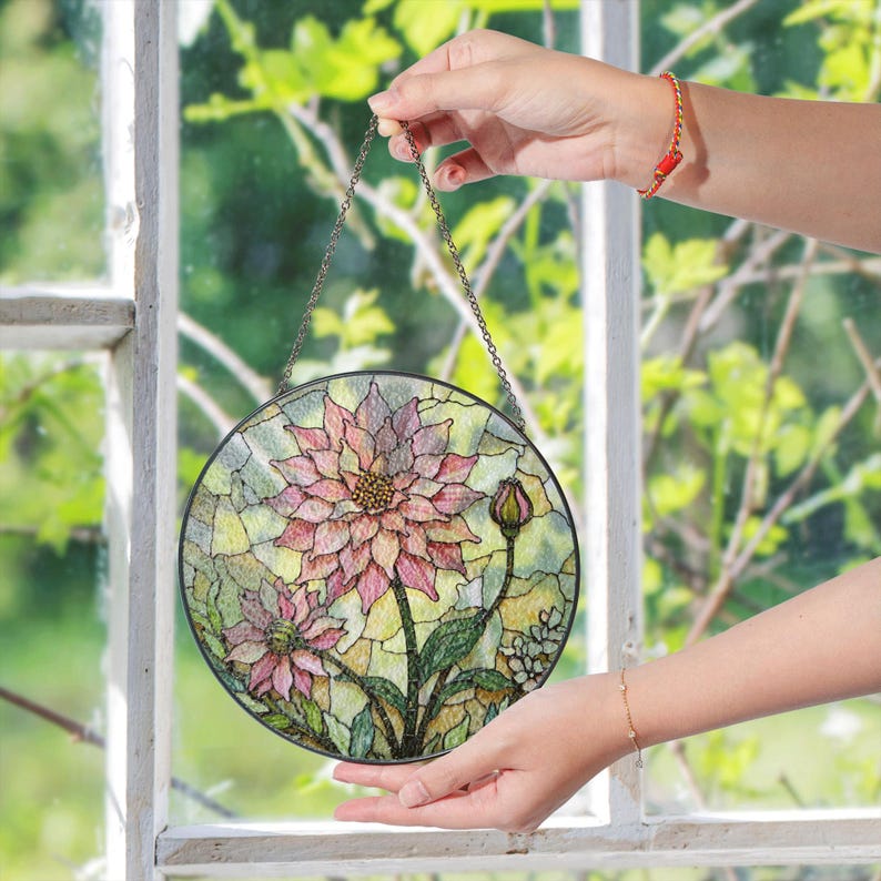 a hand holding a stained glass flower hanging from a window