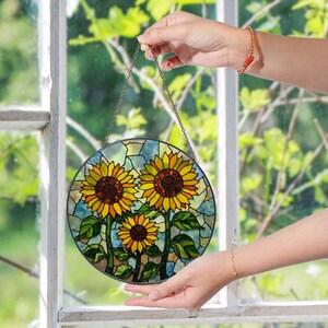 a hand holding a stained glass sunflower decoration
