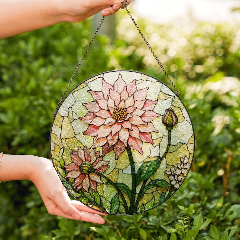 a hand holding a stained glass flower on a chain