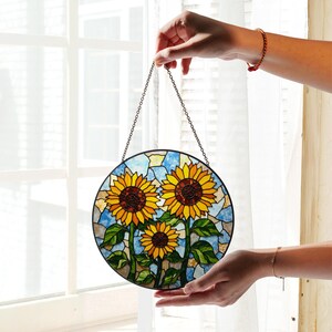 a hand holding a stained glass sunflower decoration