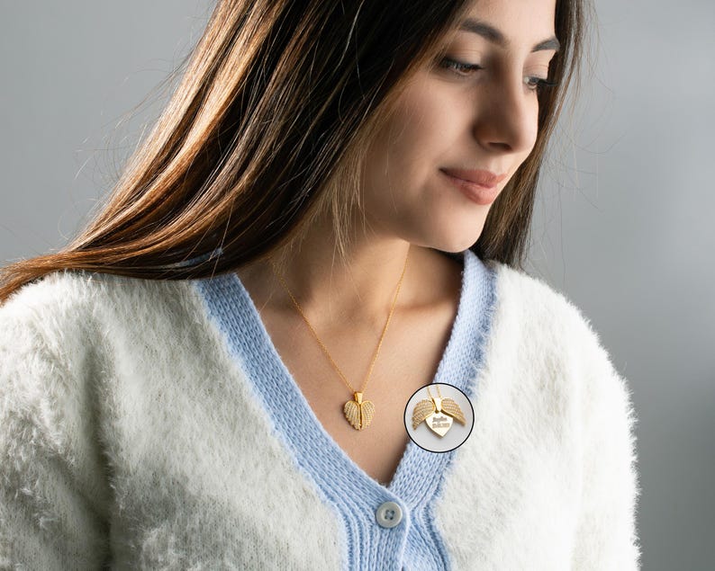 May include: A gold necklace with a heart-shaped pendant featuring angel wings. The pendant has an inscription that reads "Always in my heart".