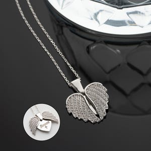 May include: Silver necklace with a heart-shaped pendant featuring angel wings adorned with sparkling cubic zirconia stones.