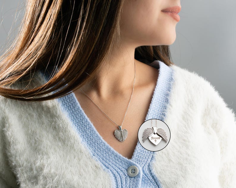 May include: A silver necklace with a heart pendant featuring angel wings. The pendant is open to reveal a smaller heart inside.