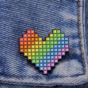 May include: A rainbow pixel heart pin on a blue denim jacket.