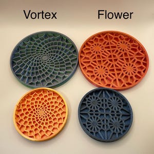 May include: Four round coasters with geometric designs. Two coasters have a blue and green color scheme with a vortex pattern. The other two coasters have a flower pattern, one is orange and the other is blue.