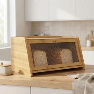 May include: A rectangular bamboo bread box with a light wood grain finish and a front-facing drop-down door. The door features a clear, vertically ribbed glass panel that reveals two loaves of sliced bread stored inside the container.