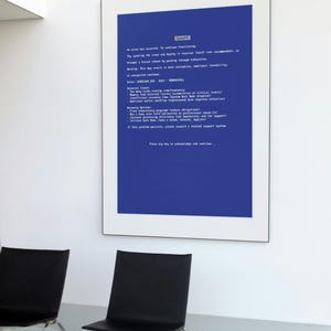 May include: A framed print with a blue background and white text, resembling a computer error message. The text includes warnings and recovery options. Two black chairs are in the foreground.