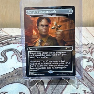May include: A collectible card titled "Dwight's Weapon Stash" featuring a portrait of a man holding a ninja star. The card is a sorcery with text and a quote. The card is in a protective sleeve.