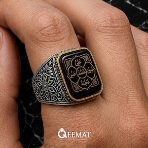 Peut inclure: Une bague en argent avec une pierre noire rectangulaire bordée d'or. La pierre est gravée d'un motif floral contenant une calligraphie arabe. L'anneau en argent présente des gravures florales complexes sur les côtés et une finition texturée.