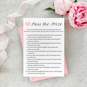 May include: A pink and white card with a heart and the text "Pass the Prize" printed on it. The card includes instructions for a game where guests pass a prize around the group based on different criteria.