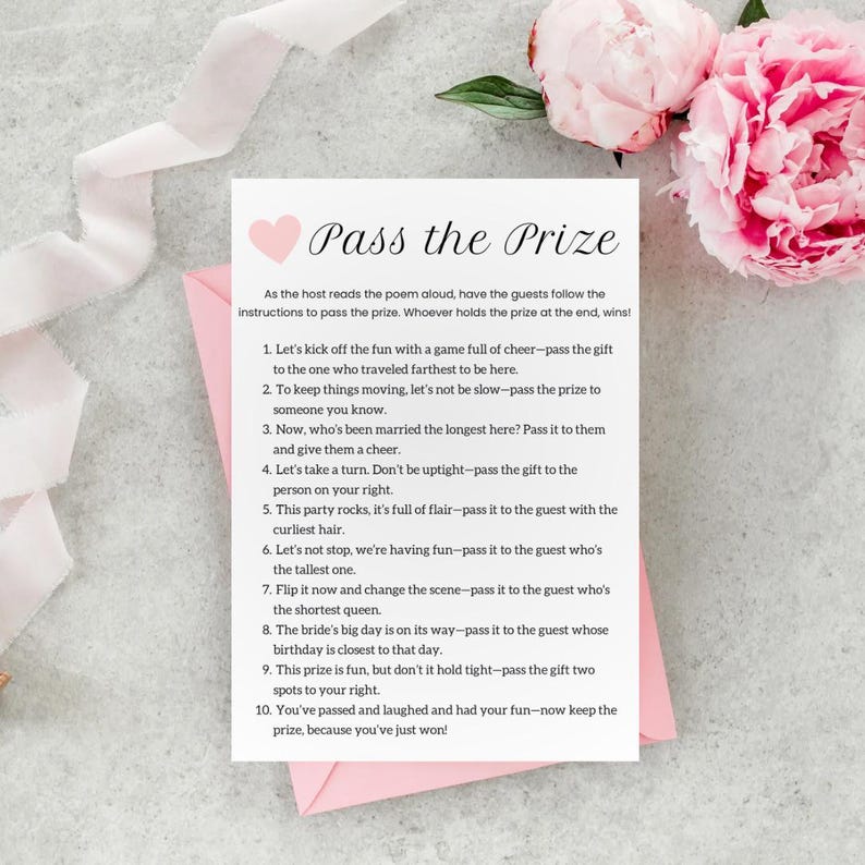 May include: A pink and white card with a heart and the text "Pass the Prize" printed on it. The card includes instructions for a game where guests pass a prize around the group based on different criteria.