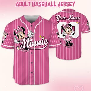 May include: Pink and white striped adult baseball jersey featuring Minnie Mouse. The front displays Minnie with the word "Minnie" in cursive. The back has the text "Your Name" above a number. The sleeves have Minnie Mouse graphics.