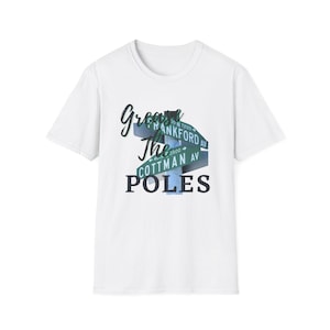 May include: White t-shirt with a graphic that reads "Grease The Poles" in a stylized font. The graphic includes street signs for Frankford Ave and Cottman Ave in green and white.