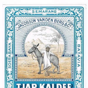 Puede incluir: Una etiqueta vintage con un borde azul y diseños florales ornamentados. La etiqueta presenta un dibujo de un burro y una persona en un entorno desértico. El texto en la etiqueta dice "SOERABAYA TJAP KALDEE CHERIBON SEMARANG JACOBSON VANDEN BERG &C? BATAVIA".