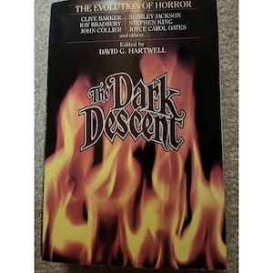 May include: A paperback book titled The Dark Descent, The Evolution of Horror, edited by David G. Hartwell. The cover features a black background with a large, stylized title in white and red, and a graphic of orange and yellow flames at the bottom.