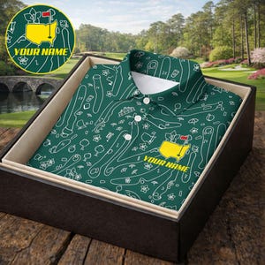 May include: A green golf polo shirt with a white course map design, presented in a black gift box. The shirt features a yellow and red logo with the text "YOUR NAME". The background shows a golf course.