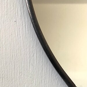 May include: Close-up of a white painted wooden surface with a black curved edge. The edge is smooth and appears to be part of a mirror frame.