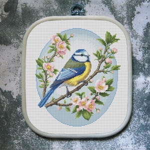 Może przedstawiać: Zestaw trzech ceramicznych kubków z nakrapianym, matowym wykończeniem. Kubki są w odcieniach kremu, jasnoszarym i ciemnoszarym. Każdy kubek ma prosty, minimalistyczny design.